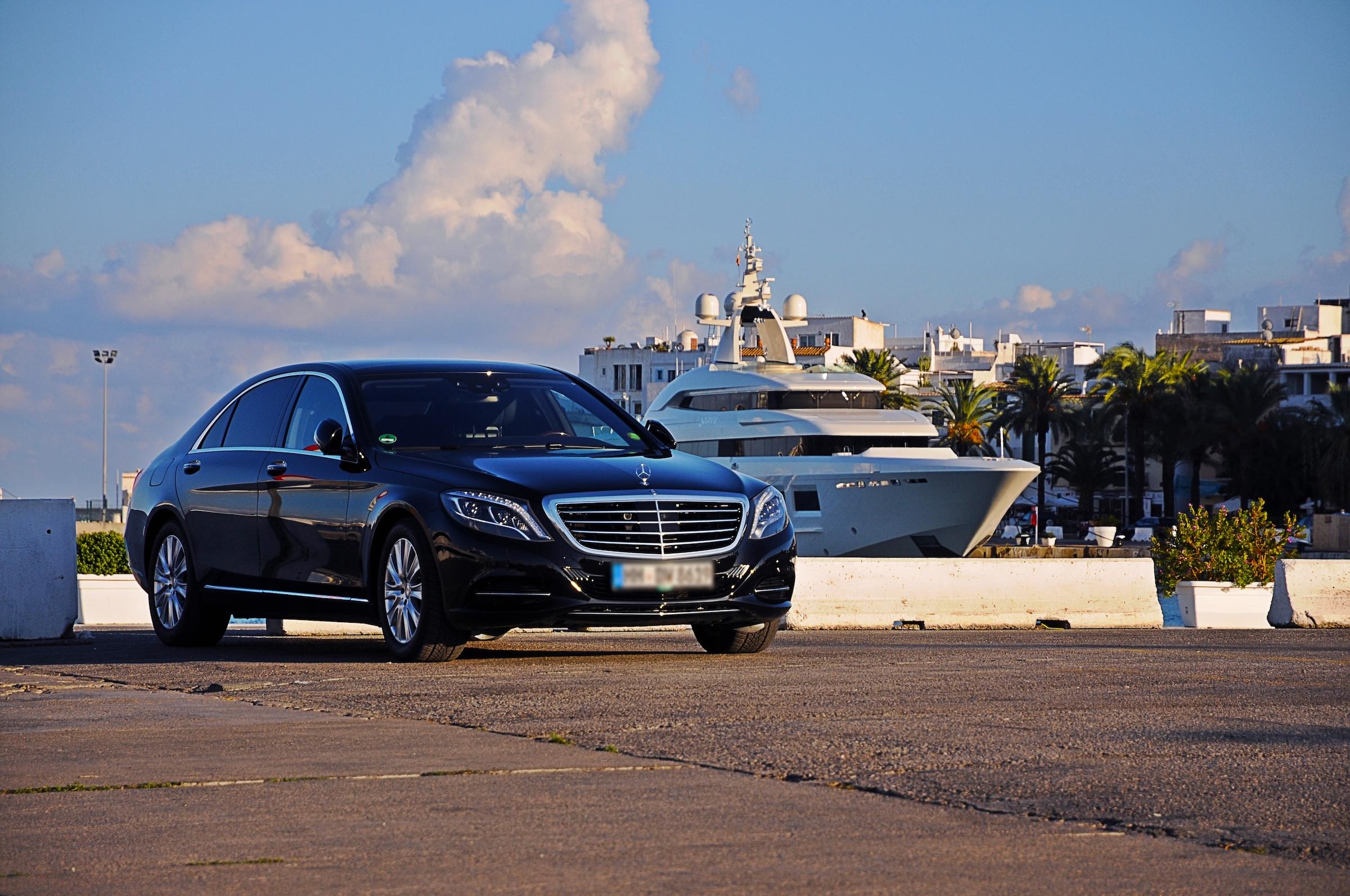 Luxury mercedes limousine in the harbour of ibiza with a private yacht in the background. I